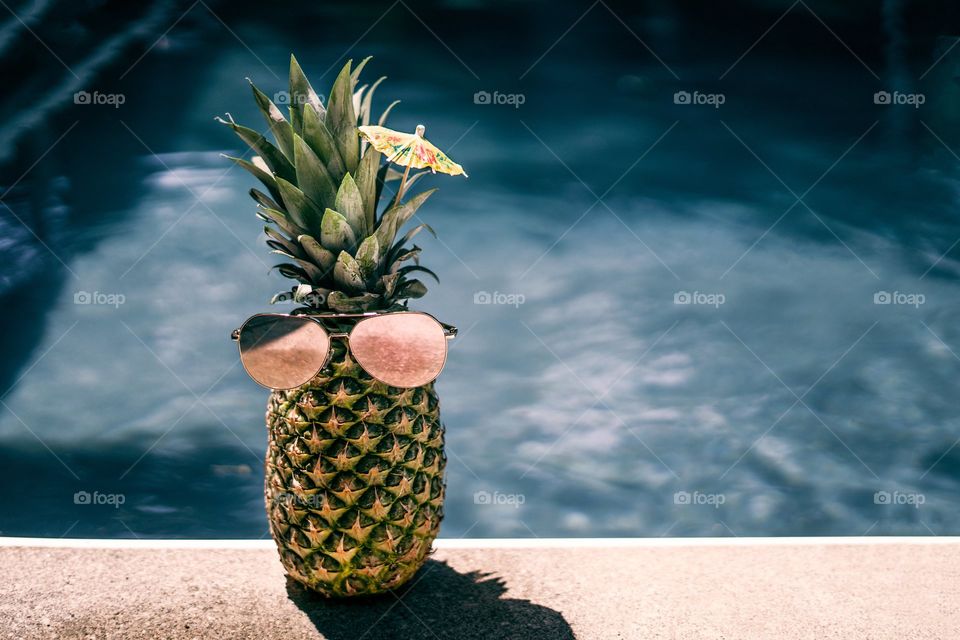 A pineapple proves it can also hang out at the pool party by wearing some reflective shades.