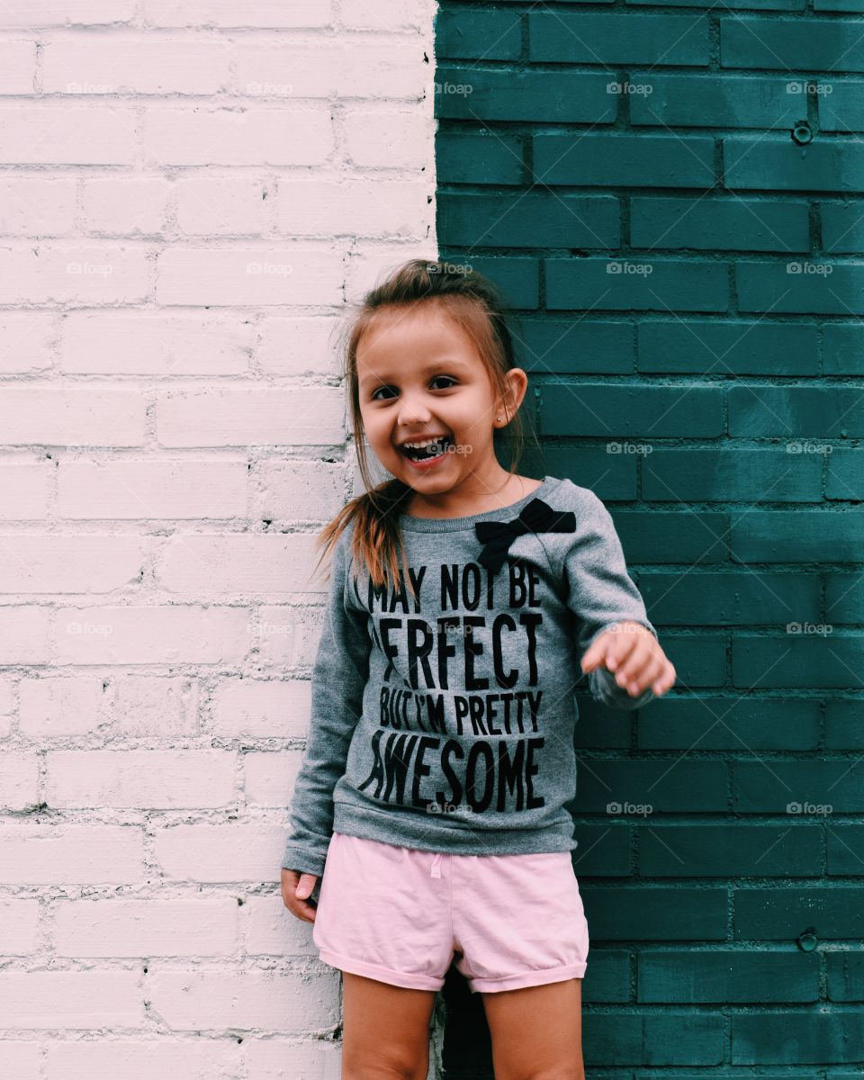 Smiling girl standing against wall