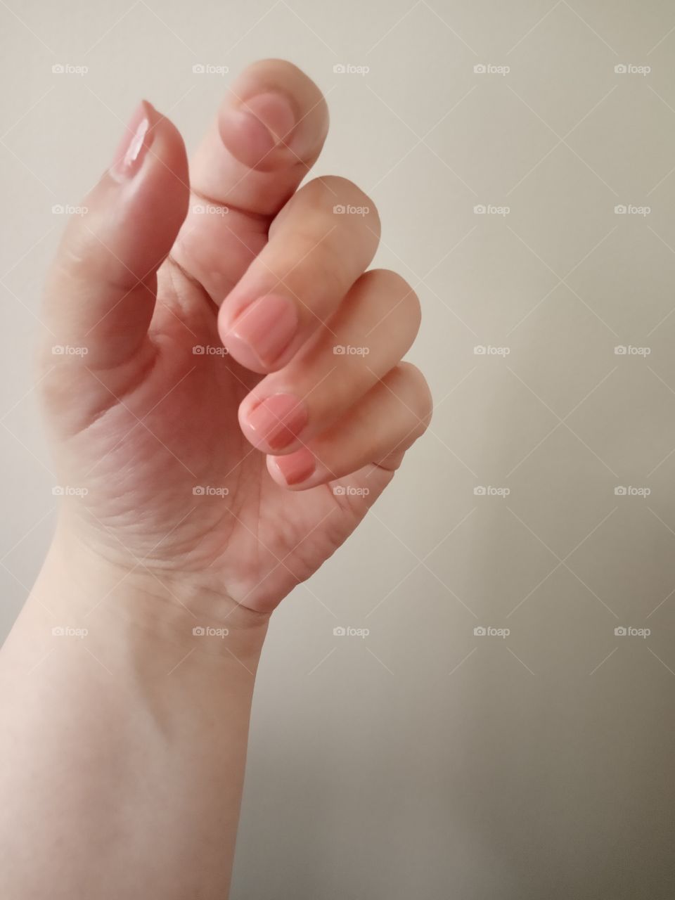 women hand with short manicure nails, with nude nail polish.