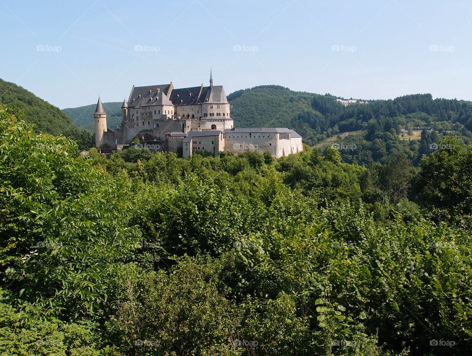 Chateau Vianden in Luxembourg sits amongst the green hills on a summer day. 