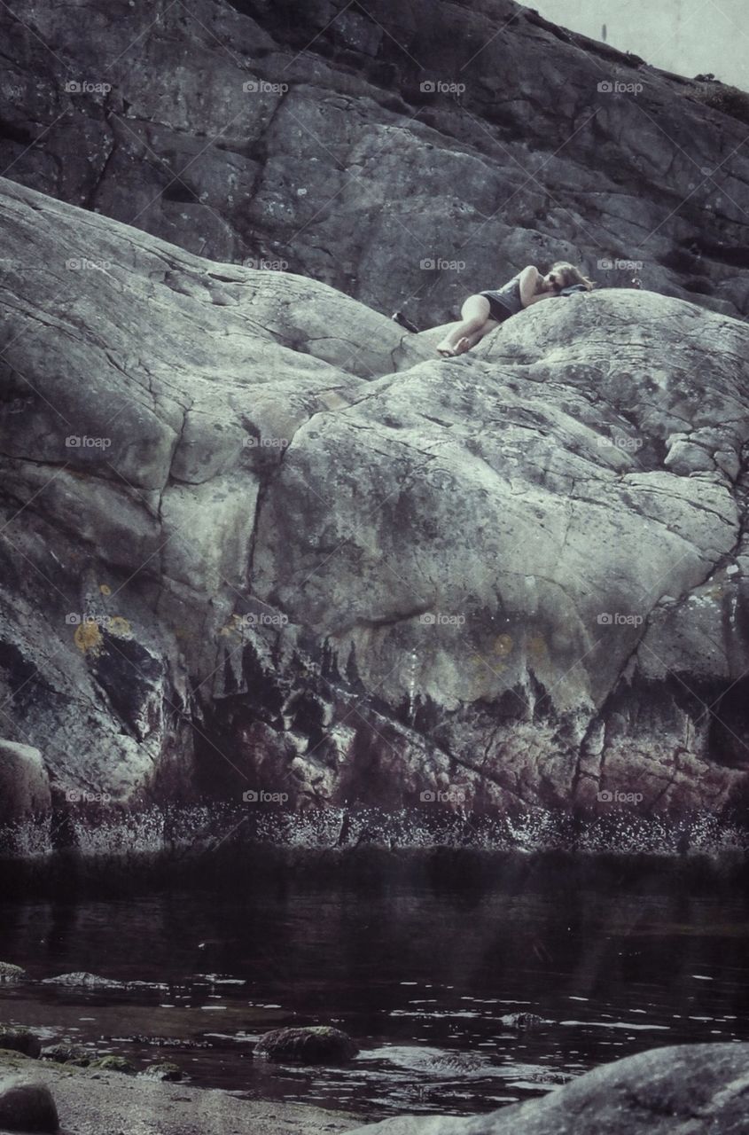 Woman sleeping on rock at beach