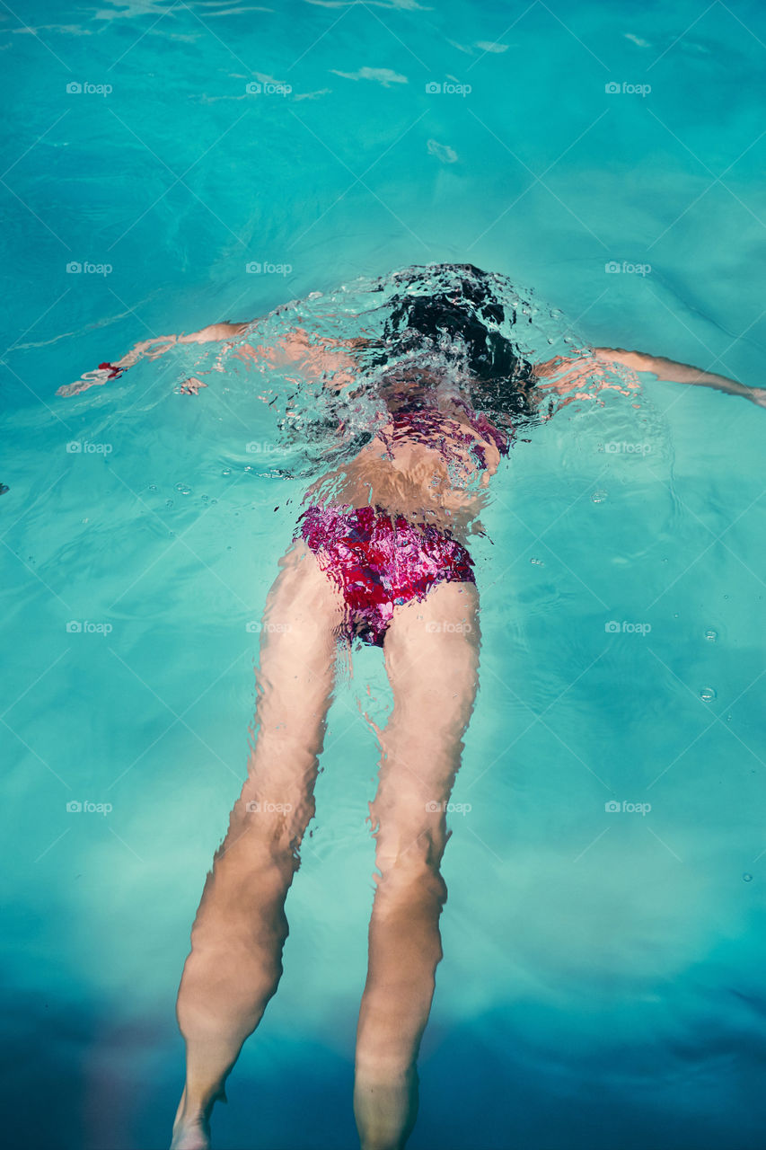 Young woman swimming and relaxing in swimming pool. Candid people, real moments, authentic situations