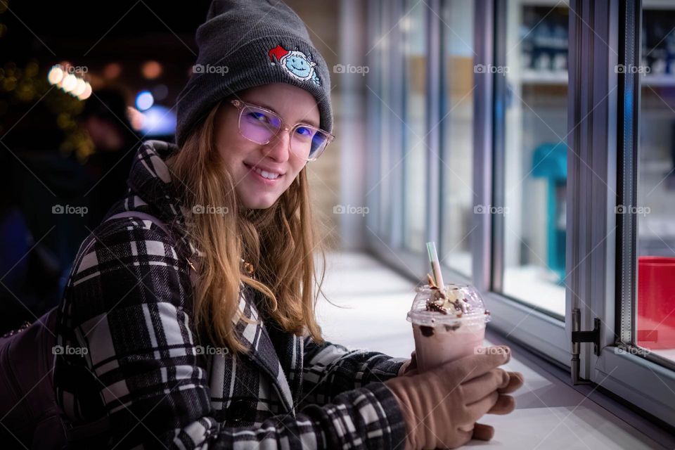 A young woman enjoys a frosty drink on a frosty evening. 