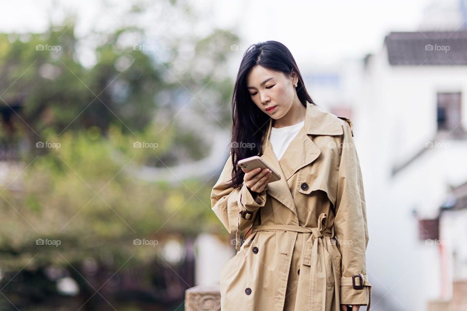 Young Asian woman using mobile phone outdoor 