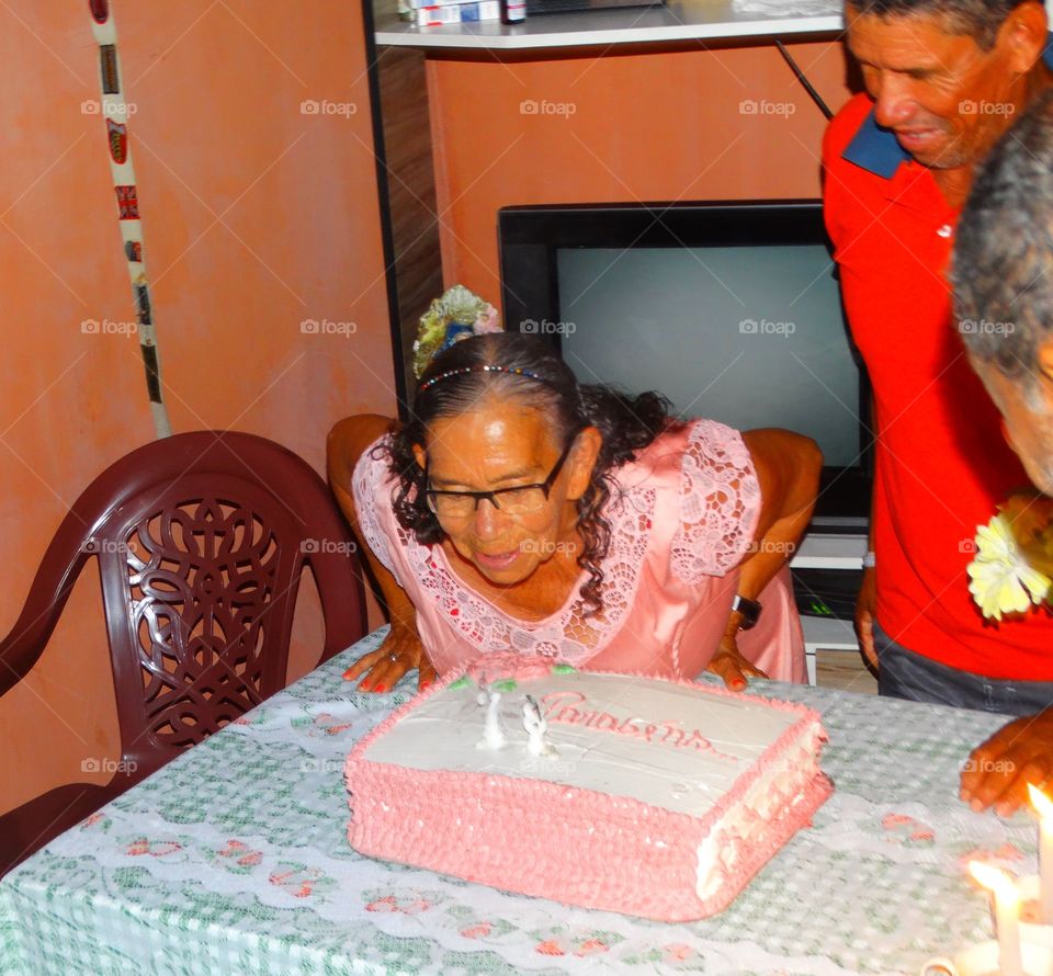 Blowing candle. An old woman blows the candle of her birthday cake