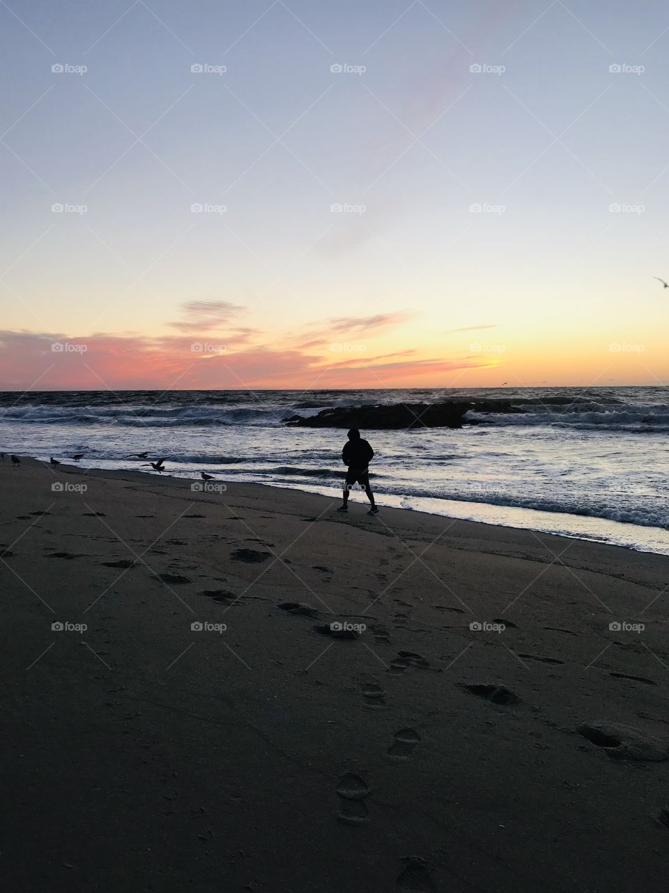 Man walking on the beach at sunrise