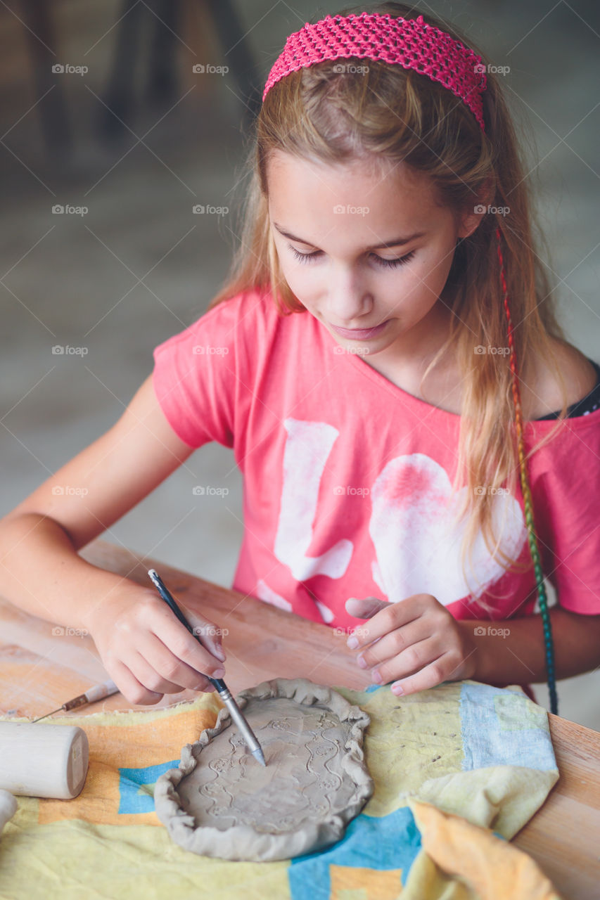 Girl making design on mud clay