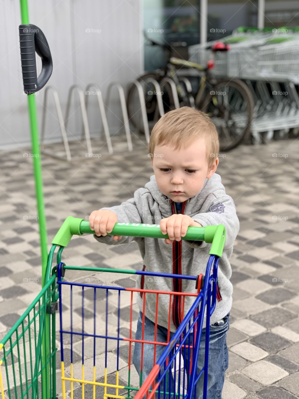 focused child rolls a supermarket stroller