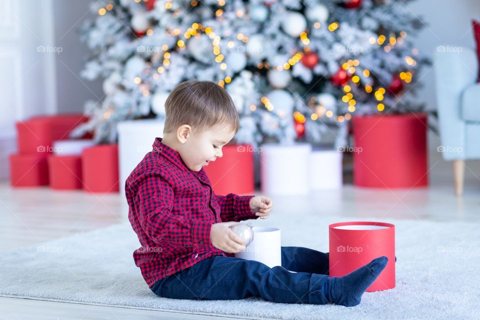 boy and gift box next to christmas tree
