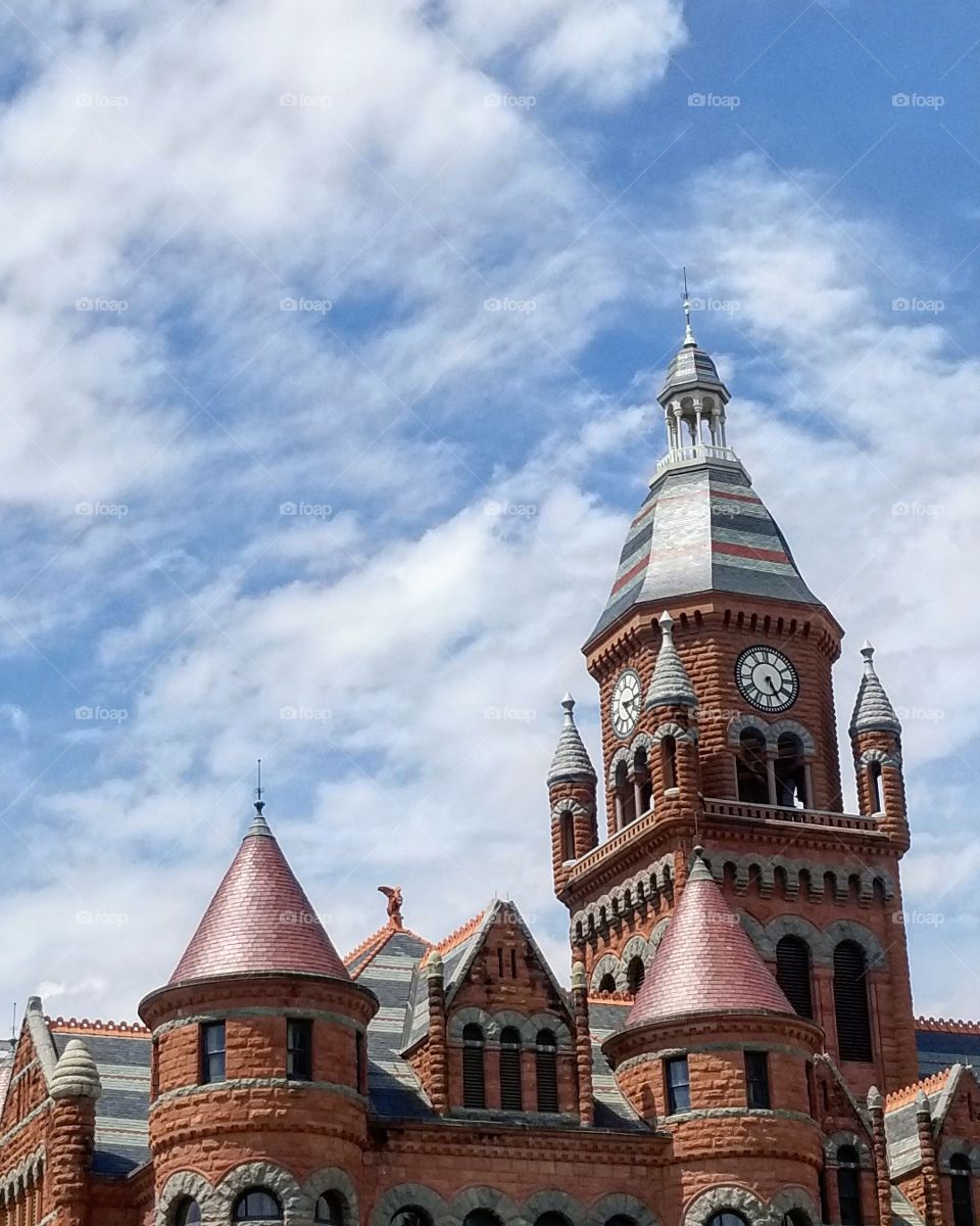 Red castle like museum building in Dallas against blue skies and white clouds