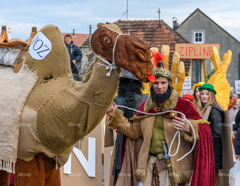 Portrait of man in roman centurion costume, holding a fake camel at carnival