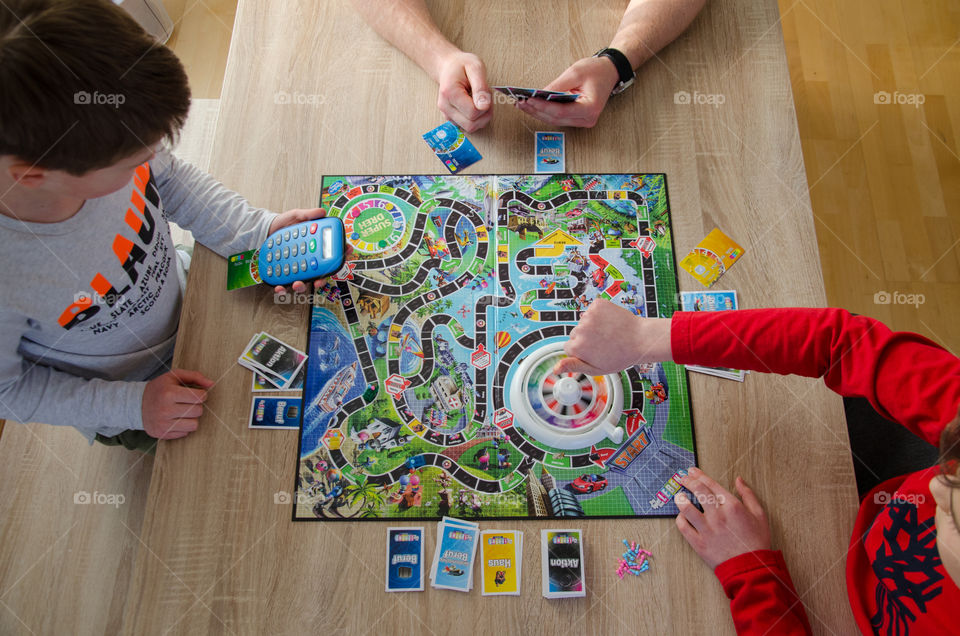 Kids and father are playing together a board game at home.