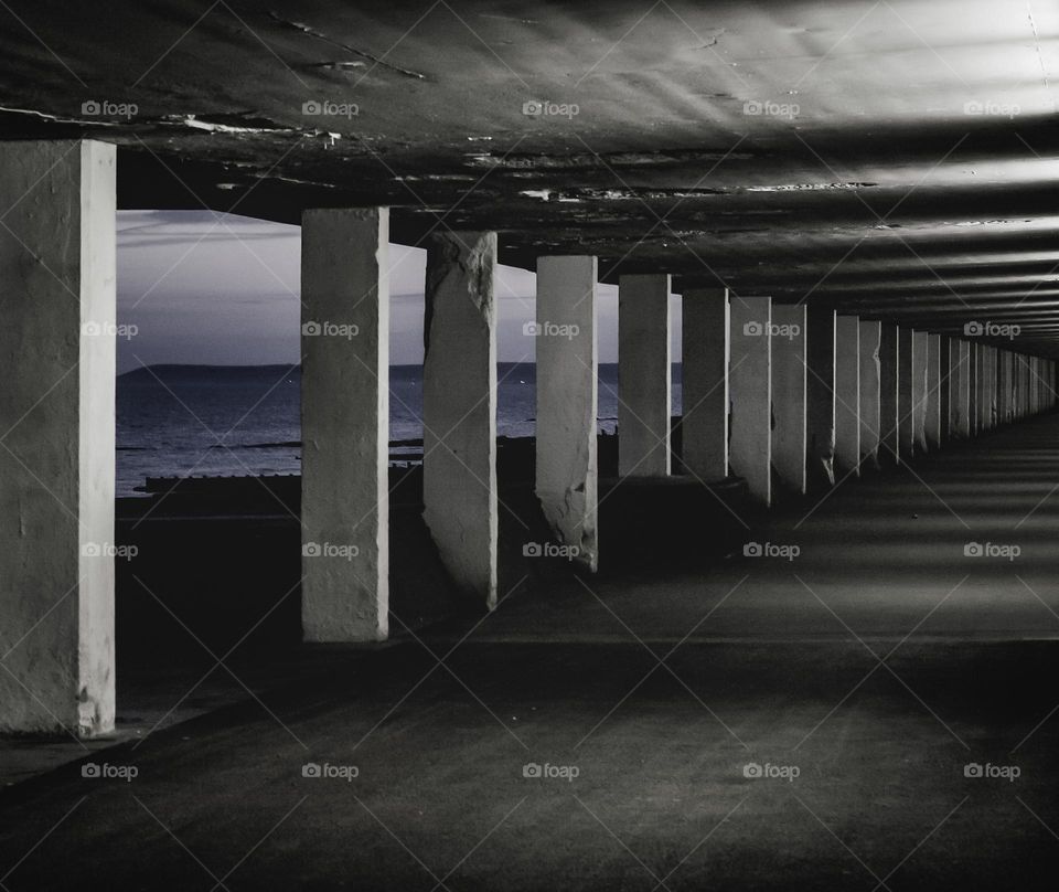 A pedestrian underpass that runs along the seafront at dusk, with a view out to Beachy head 