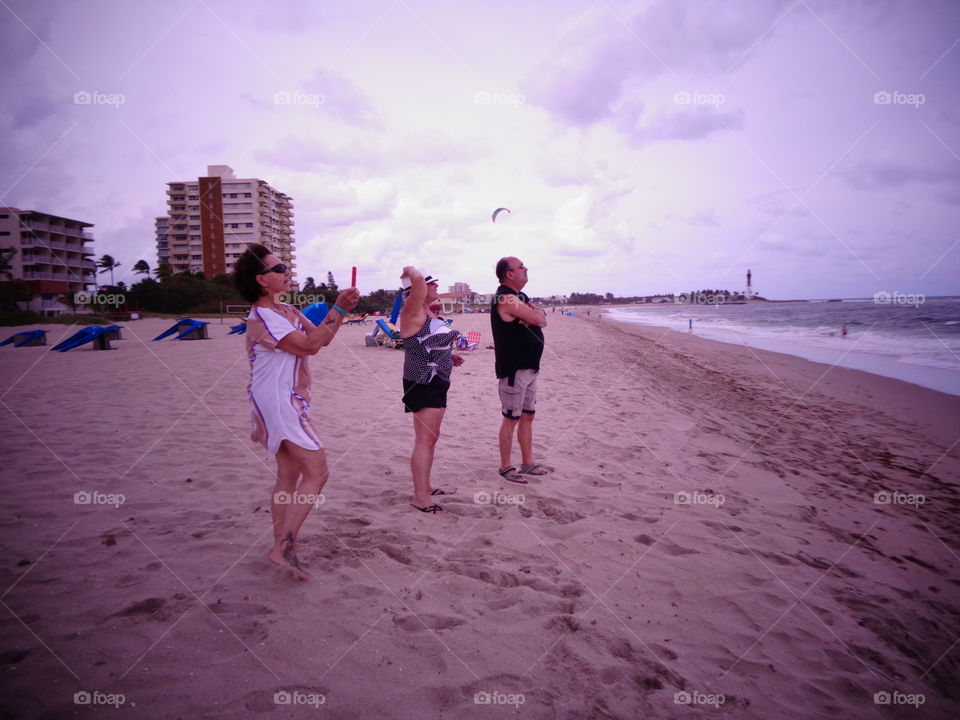 People watching something from the beach out on the ocean. No other people around.