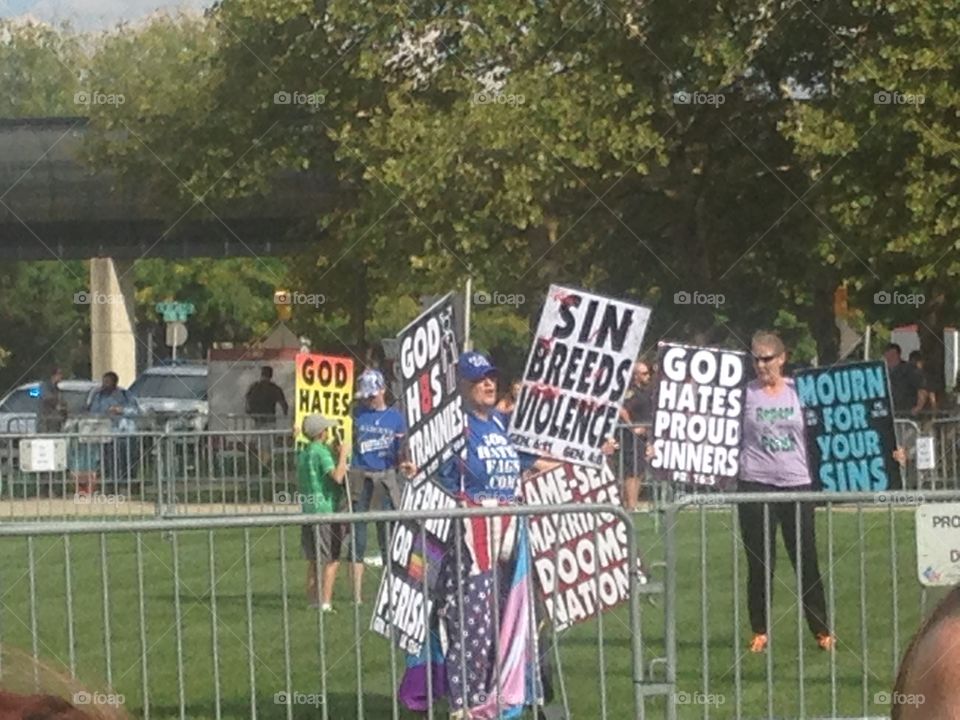 Westboro Baptist church members holding signs to protest an LGB club formed by students of IUPUI.  Club supporters and spectators stand in the background.