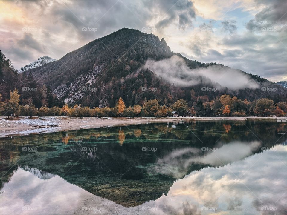 Scenic view at the foggy mountain reflected in the natural lake in Slovenia.