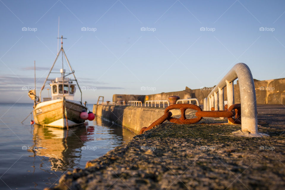 A boat docked at sunset on a pier in Cahore, County Wexford, Ireland