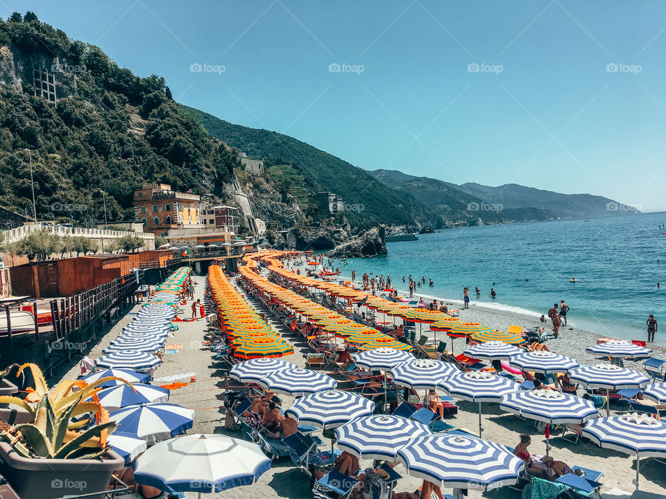 Busy beach of Moneterosso al mare. Warm breeze and bright sunshine signifies the happiest summer time. Let’s go tan ! 