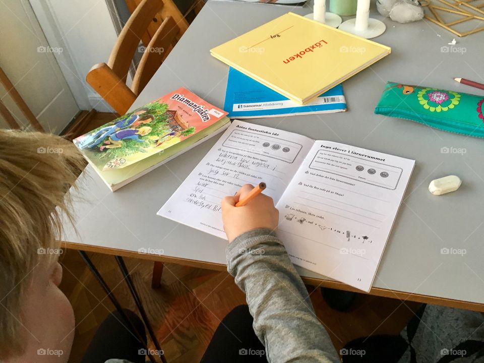 Boy doing homework in kitchen, from behind.