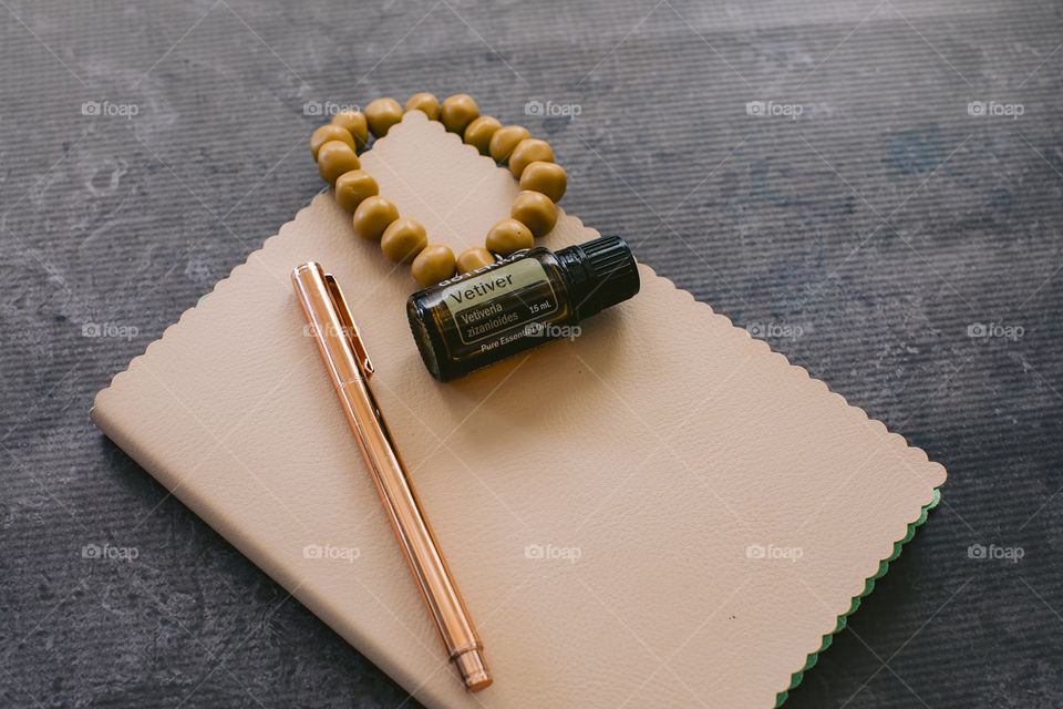 Vetiver doterra essential oil bottle on cream notebook with rose gold pen & mustard bead bracelet 
