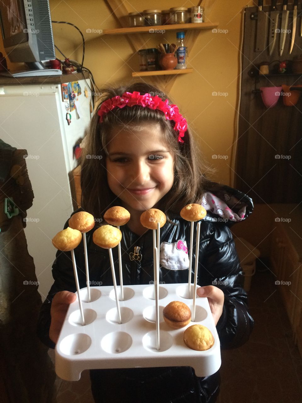 Happy girl holding muffin in baking tray