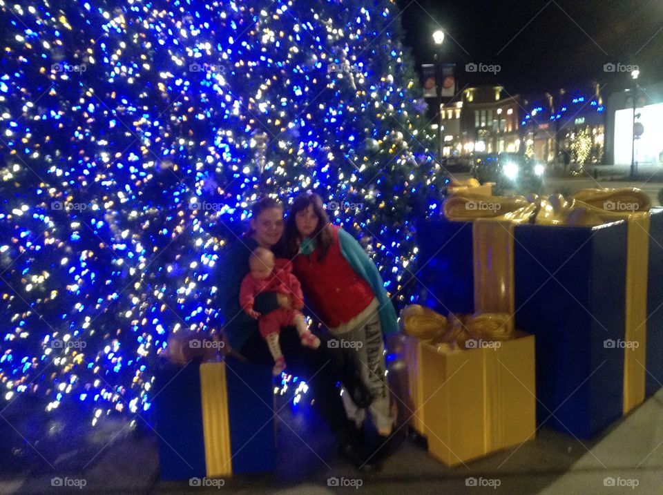 Siblings with baby sister with Down syndrome in front of blue and white Christmas tree