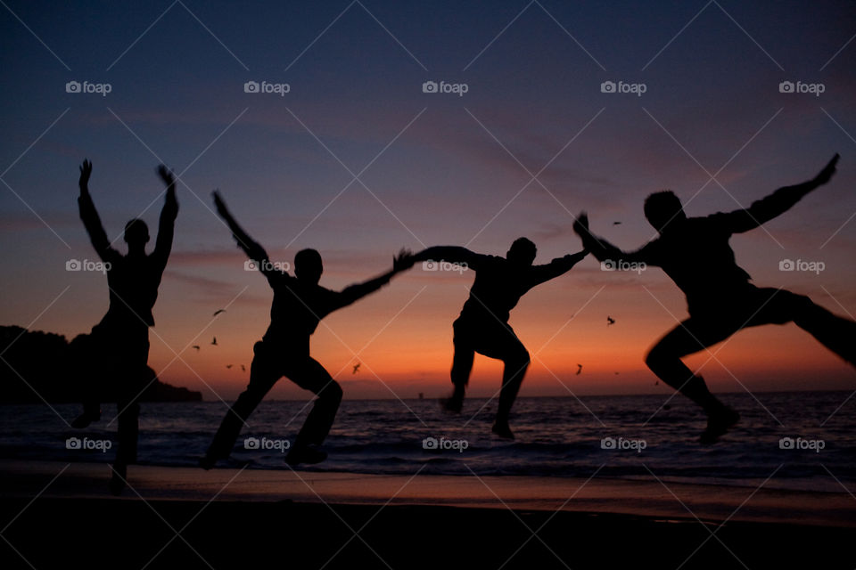 Jumping groomsmen on the beach during sunset 