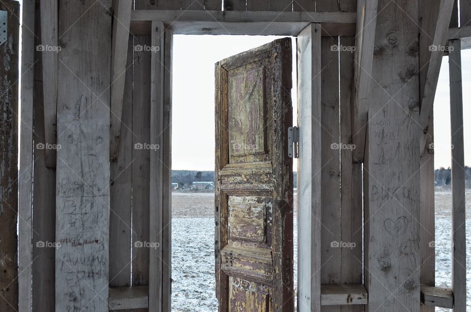 Shabby rustic doorway in rural ruins, view to winter frozen landscape 