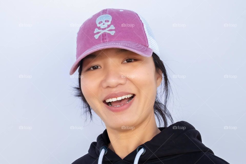 A young lady of Taiwanese descent has fun showing off her sparkly cap. 