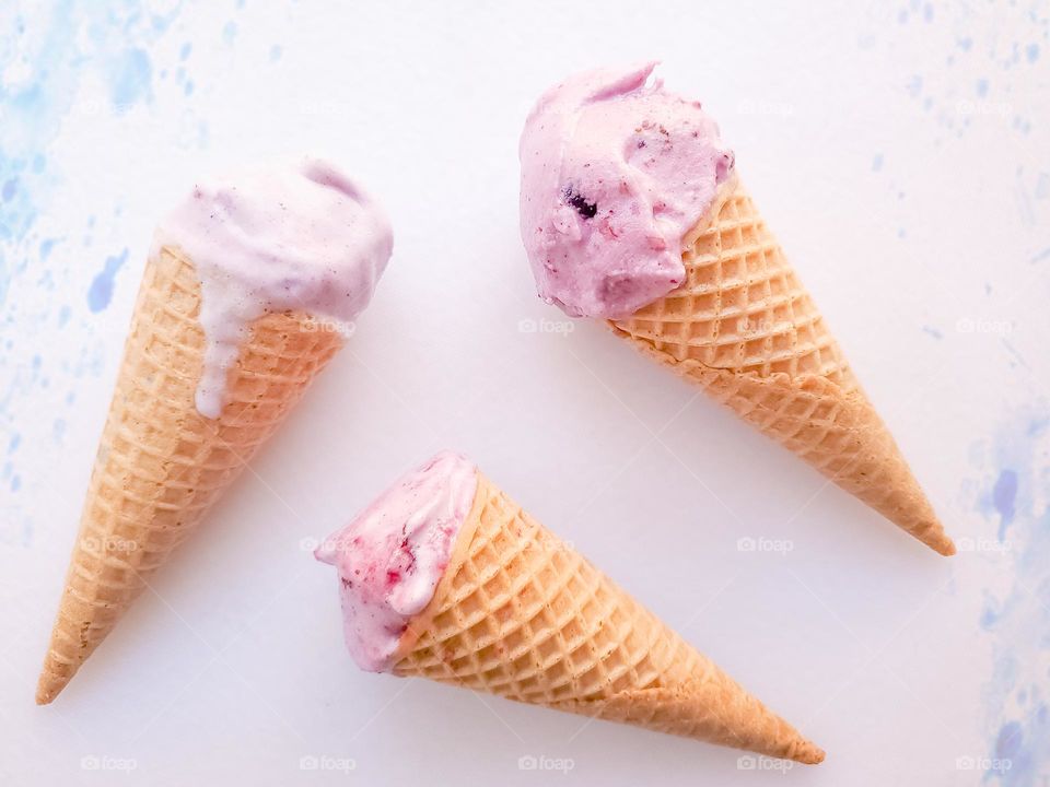 Three pastel pink ice-cream cones in various stages of being consumed.