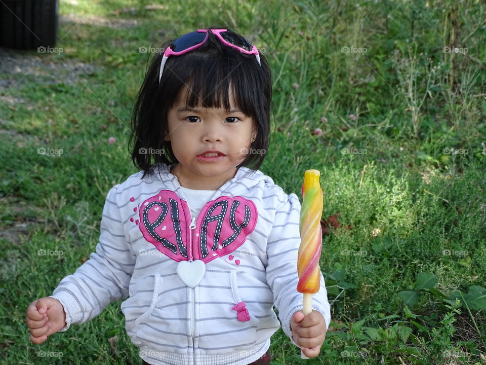 A little girl with popsicle ice standing on grass