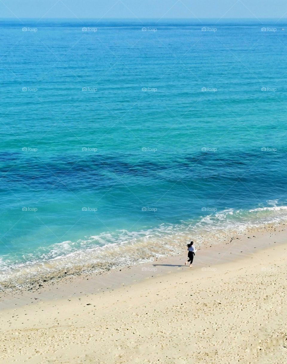 Beautiful sunny day in England. Blue sea and the girl goes in for sports, runs along the seashore. Healthy lifestyle. Sport time.