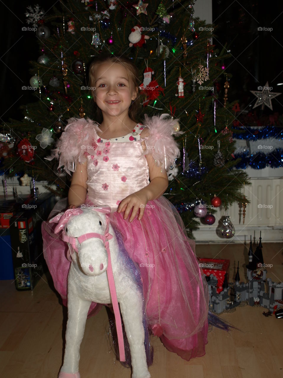 little princess sat on a unicorn. in front of the family Christmas tree
