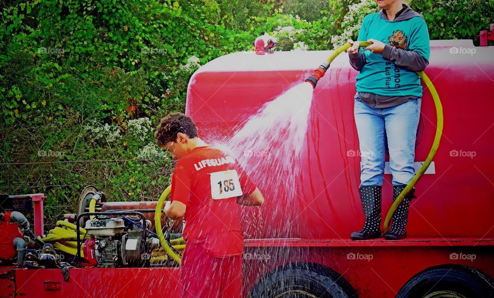 Cooling off under a firehose after hot summer day road race. 