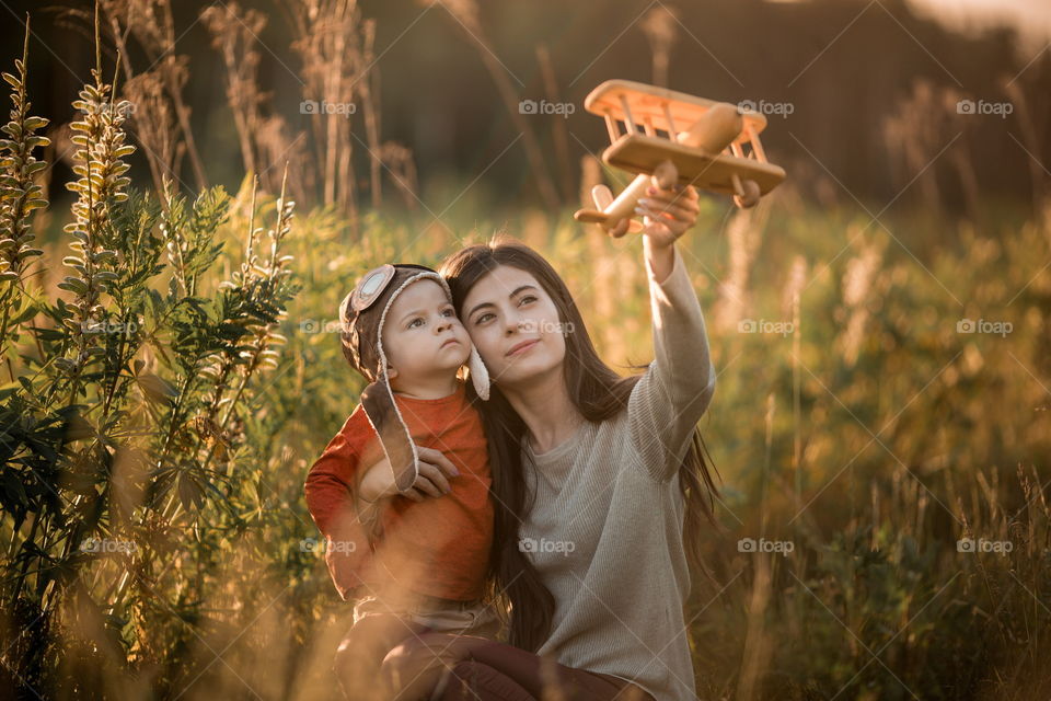 Mother and son with wooden plane at sunset