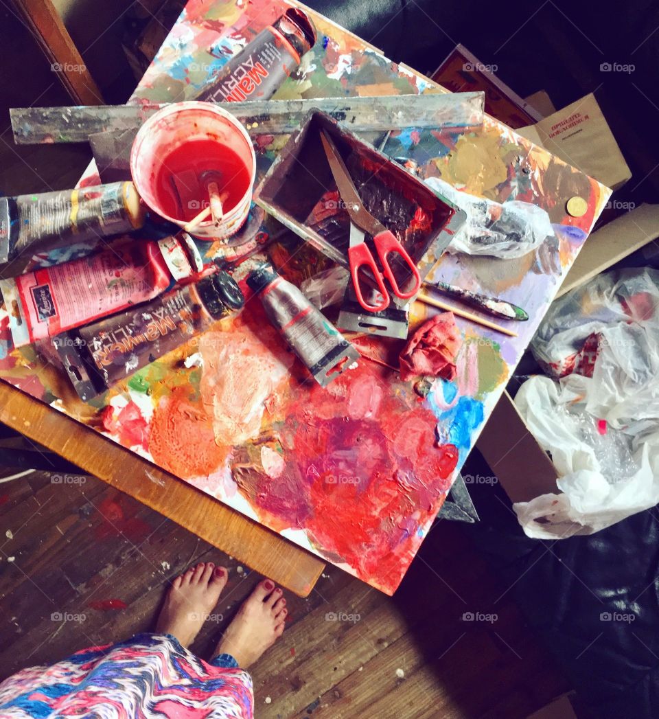 Drawing at home with oil colors. Feet view of colorful painting table at painting process.