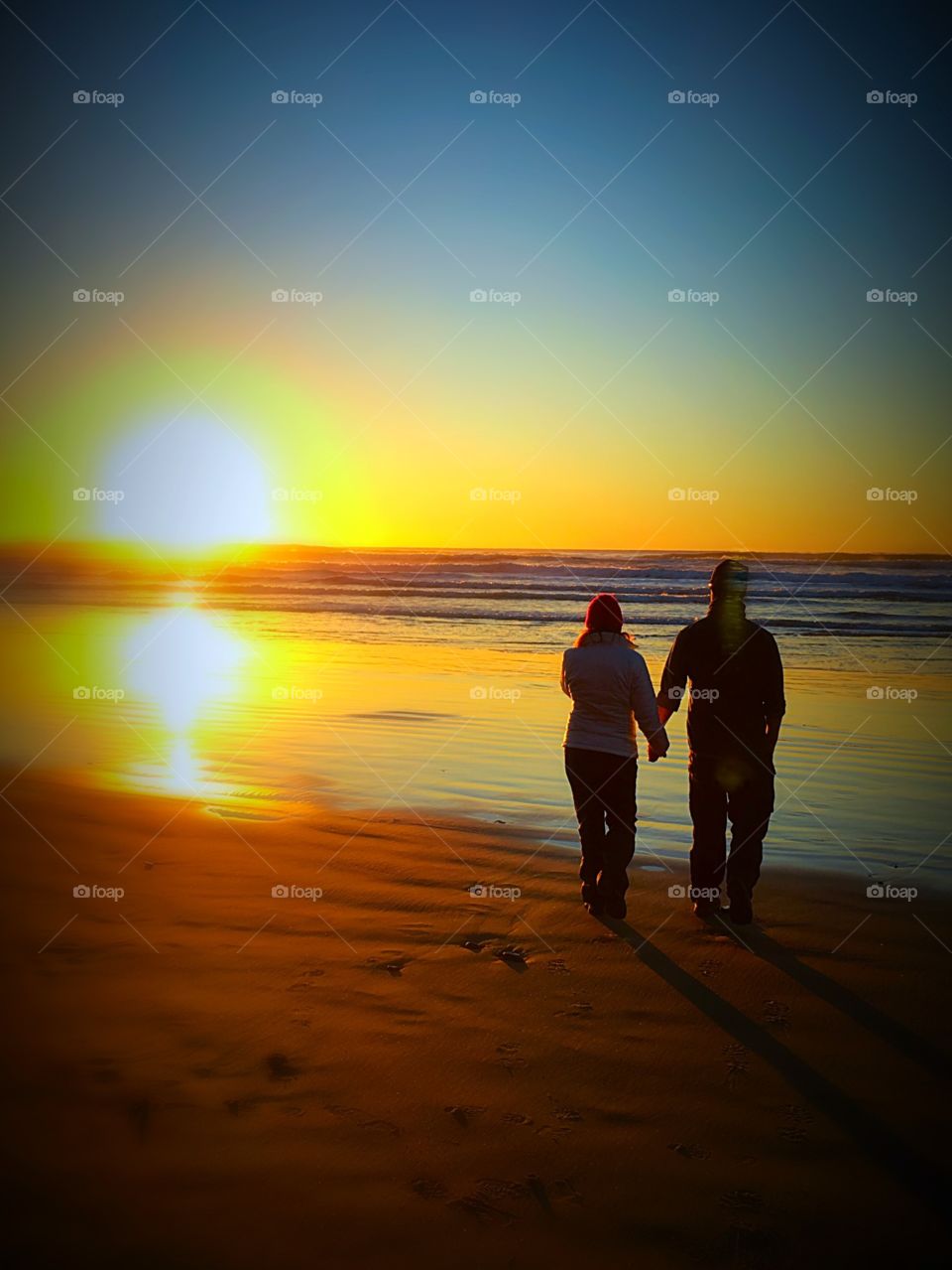 Couple holding hands in sunset silhouette