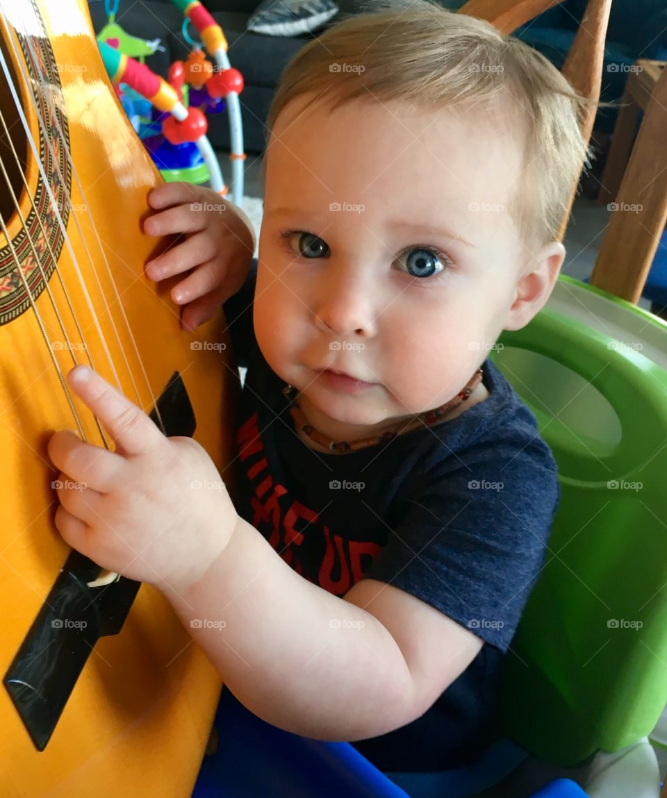 Pulling the guitar strings. Appreciating music at a young age. 