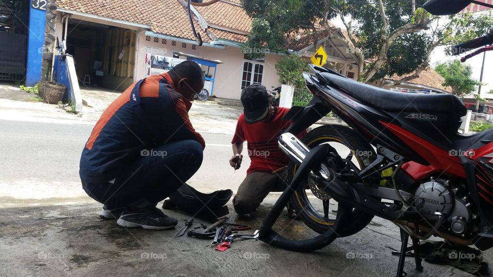 a mechanic who is repairing a motorbike