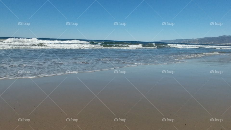 ocean sea waves on beach on clear day with blue sky