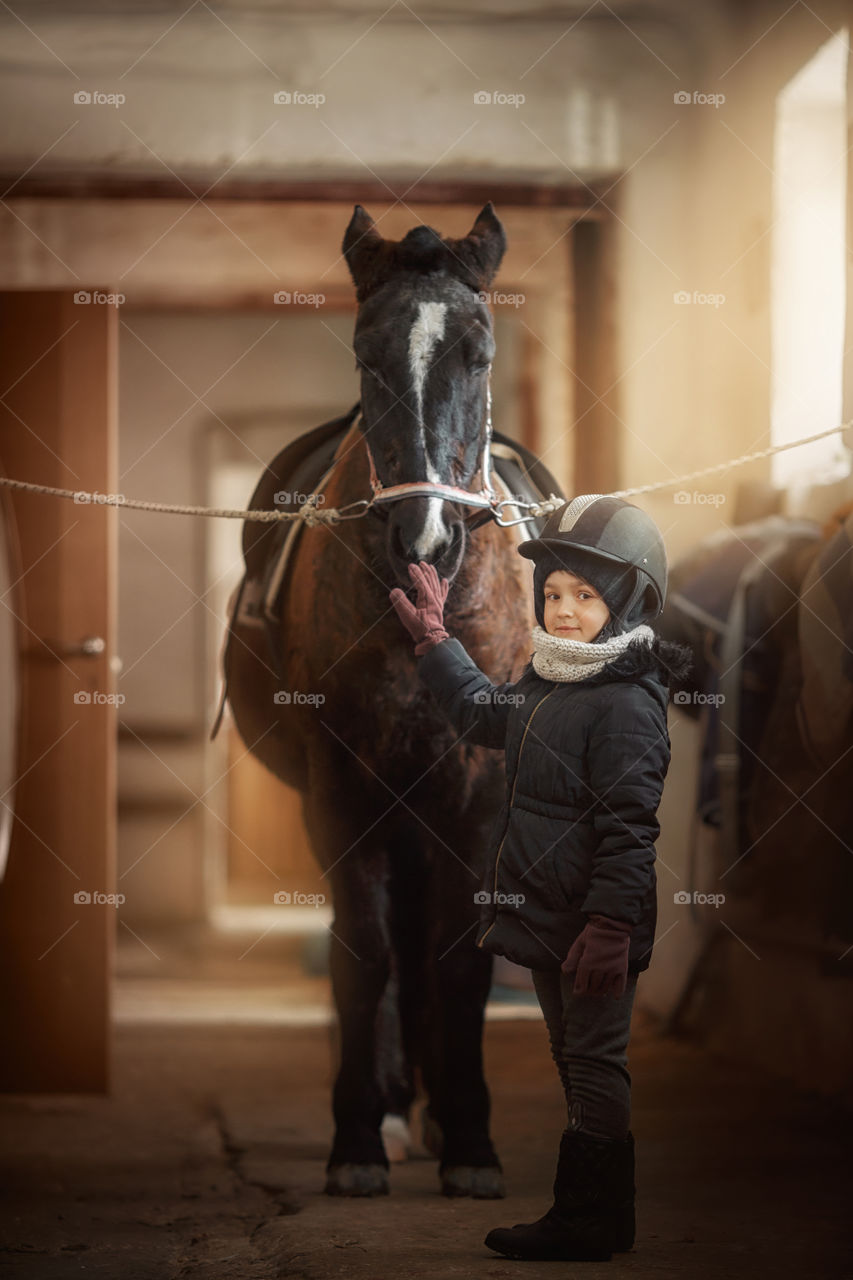 Girl in horse riding wear in a stable