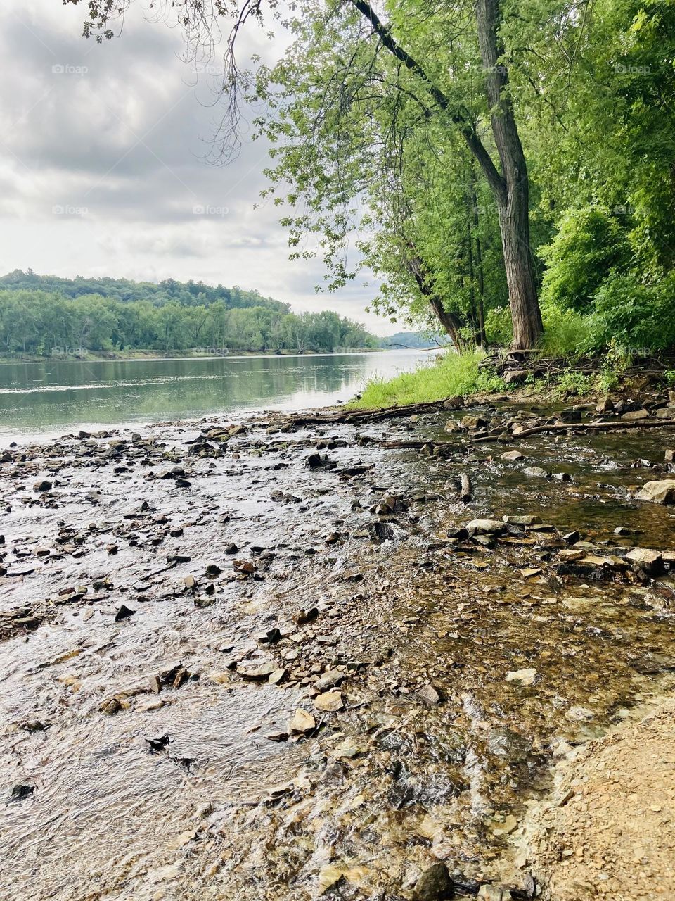 The rocky shore of the Mississippi River located in St. Paul, Minnesota during late summer with a stormy sky