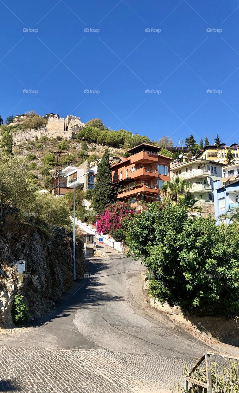 Дорога извивается вверх,уходя в далекие горы.По бокам узкой дороги стоят уютные домики , их крыши потерялись в зелени деревьев . Атмосфера спокойствия и загадочности пронизывает это пейзаж, приглашая исследовать неизведанные тропы 