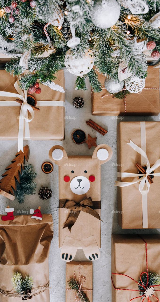 Top view of decorations and christmas presents wrapped in brown paper under christmas tree
