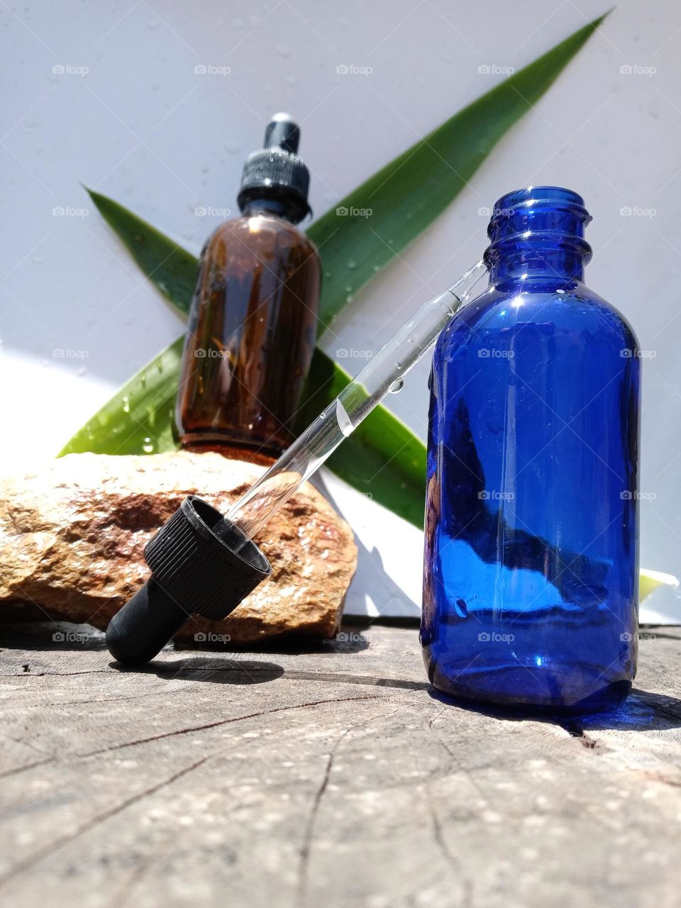 blue and amber glass dropper bottle. In nature. tree trunk.