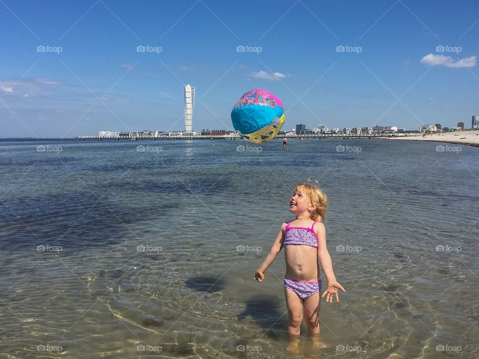 Little girl of three plays with a ball at Ribban beach in Malmö Sweden.