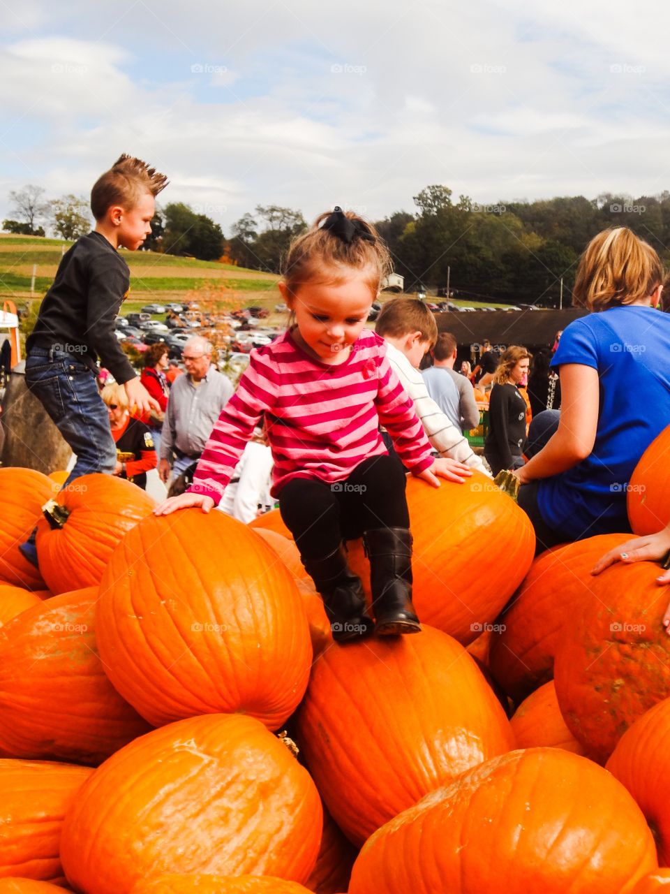 Girl sitting over the stack of pumpkin