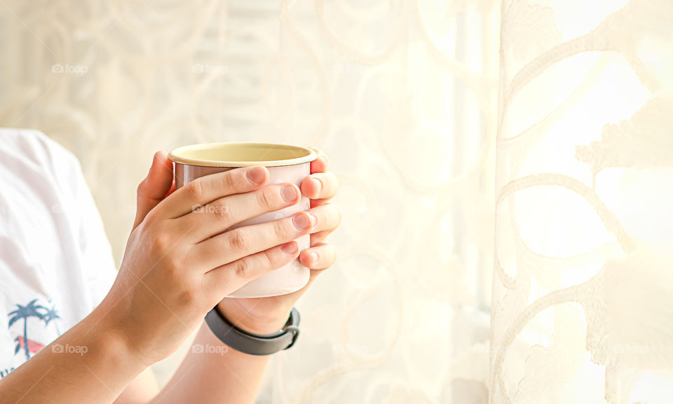 Hands holding a cup with coffee.