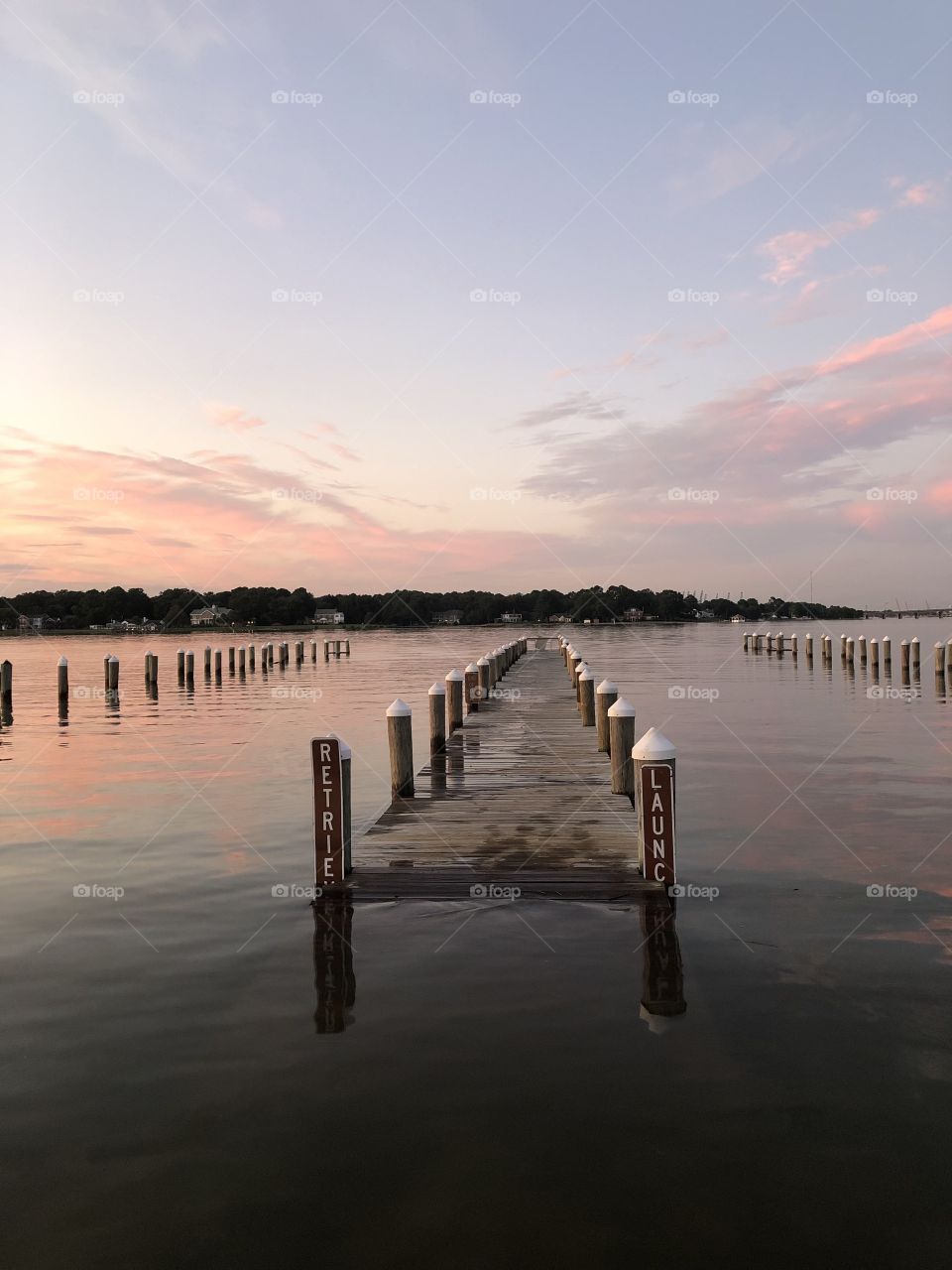 Calm waters surrounding a flooded dock under a beautiful pastel sunset sky 