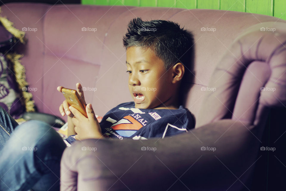 Asian little boy visible shock on handphone